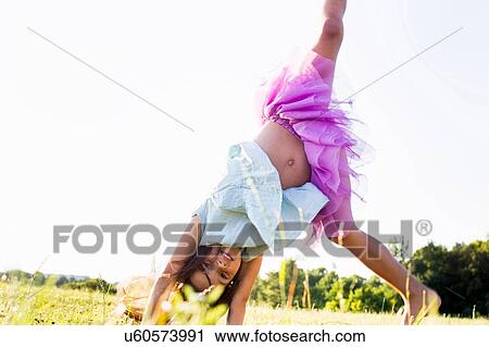 Cute girl wearing tutu cartwheeling in park View Large Photo Image Stock Image - Cute girl wearing tutu cartwheeling in park. Fotosearch