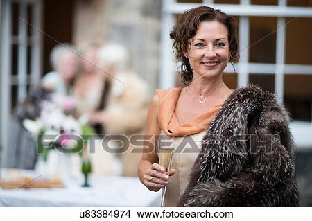 Picture - Elegant mature women enjoying champagne in urban garden. Fotosearch
