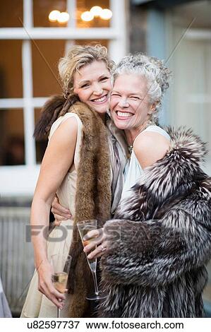 Stock Photo - Elegant mature women enjoying champagne in urban garden. Fotosearch