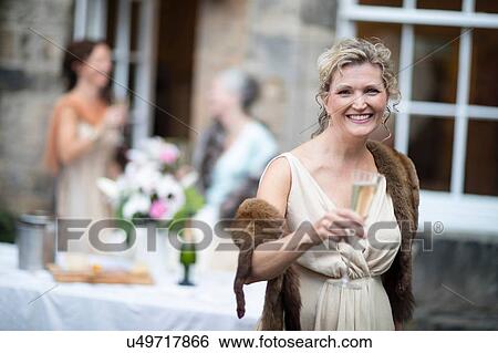 Stock Photograph - Elegant mature women enjoying champagne in urban garden. Fotosearch