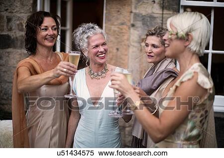 Stock Photography - Elegant mature women enjoying champagne in urban garden. Fotosearch