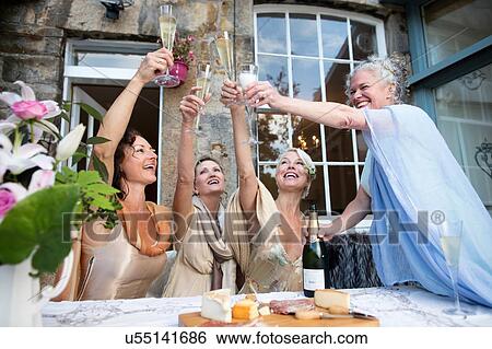 Stock Photograph - Elegant mature women toasting in urban garden. Fotosearch