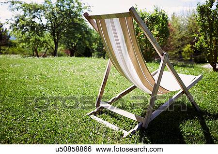 Stock Photograph - Empty deckchair in sunlit garden. Fotosearch