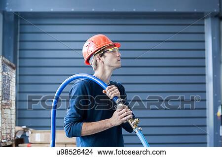 Picture - Factory engineer carrying power cable over his shoulder. Fotosearch