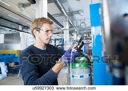 Stock Image - Factory technician checking valves in factory. Fotosearch
