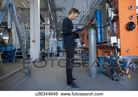 Stock Photo - Factory technician inspecting valves at control panel. Fotosearch