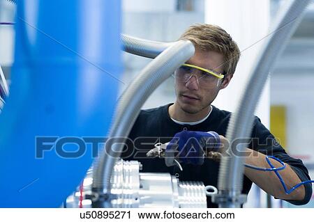 Stock Image - Factory technician maintaining network cables. Fotosearch