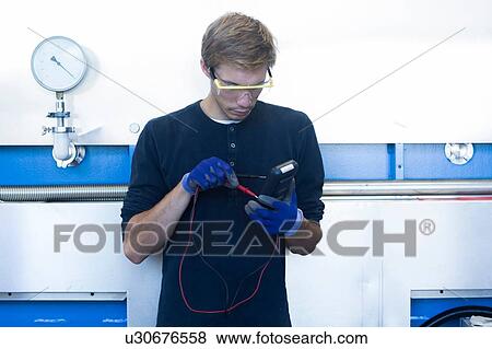 Stock Photo - Factory technician testing cable in factory. Fotosearch