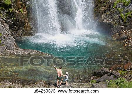 Stock Image - Father and daughter enjoying waterfall, Saut Deth Pish, Valle de Aran, Spain. Fotosearch