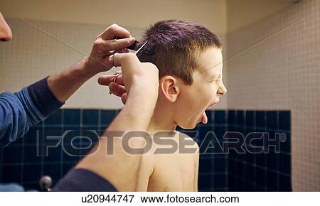 Father cutting reluctant sons hair in bathroom View Large Photo Image Stock Photo - Father cutting reluctant sons hair in bathroom. Fotosearch
