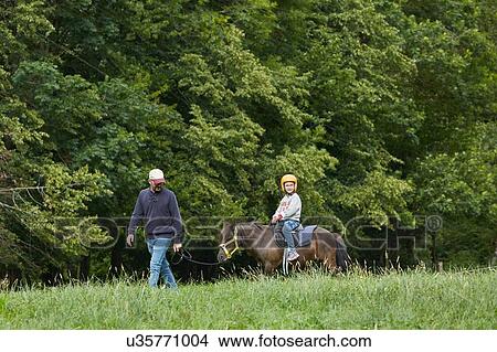 Picture - Father with daughter riding pony, Valle de Aran, Spain. Fotosearch
