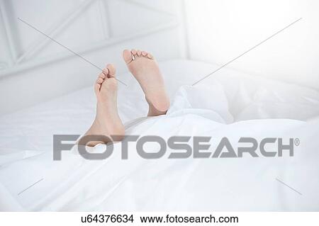 Picture - Feet sticking out of bed. Fotosearch