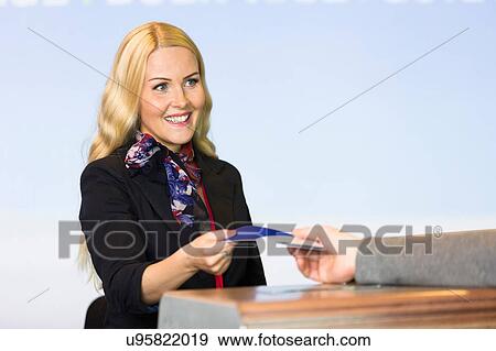 Female check in desk staff handing over boarding pass View Large Photo Image Stock Photo - Female check in desk staff handing over boarding pass. Fotosearch