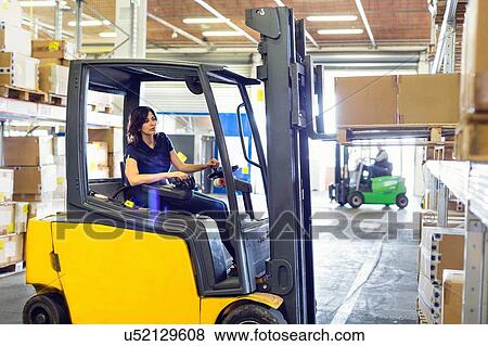 Stock Photo - Female forklift truck driver working in distribution warehouse. Fotosearch