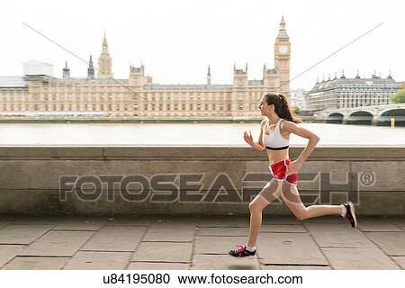 Stock Image - Female runner running on Southbank, London, UK. Fotosearch