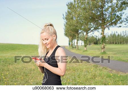 Female runner selecting smartphone music in park View Large Photo Image Stock Image - Female runner selecting smartphone music in park. Fotosearch
