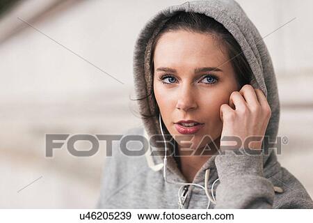 Female runner wearing grey hoody listening to music on earphones View Large Photo Image Stock Photo - Female runner wearing grey hoody listening to music on earphones. Fotosearch