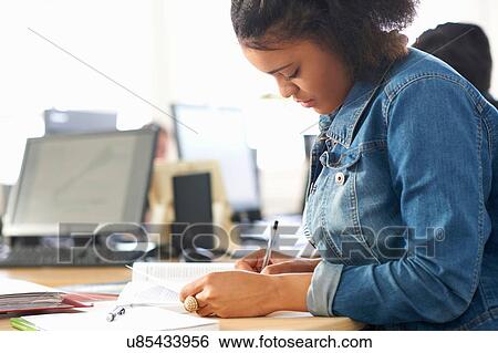 Stock Photograph - Female student writing in classroom. Fotosearch