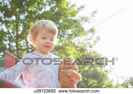 Female toddler holding teddy bear playing on park slide View Large Photo Image Stock Image - Female toddler holding teddy bear playing on park slide. Fotosearch