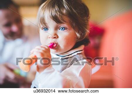 Picture - Female toddler in living room playing with toy. Fotosearch