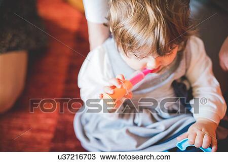 Female toddler sitting on living room floor playing with toy View Large Photo Image Stock Image - Female toddler sitting on living room floor playing with toy. Fotosearch