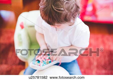 Stock Image - Female toddler untying trainer shoelaces. Fotosearch