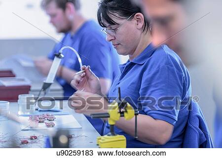 Female worker assembling electromagnets on production line in electronics factory View Large Photo Image Stock Image - Female worker assembling electromagnets on production line in electronics factory. Fotosearch