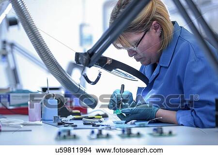 Picture - Female worker assembling electronics in electronics factory. Fotosearch