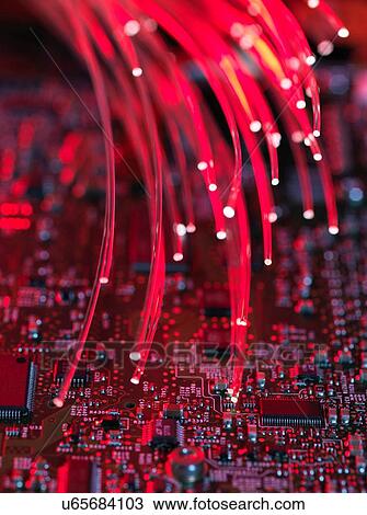 Stock Image - Fibre optics flowing through circuit boards from a laptop computer, close-up. Fotosearch