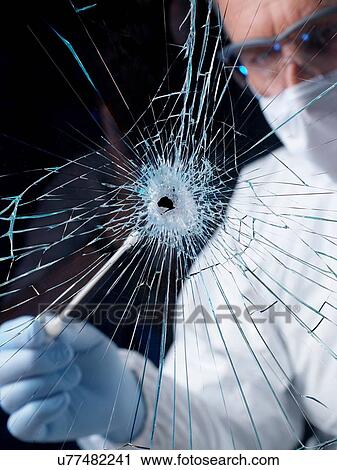 Stock Image - Forensics officer using swab to collect evidence from broken window. Fotosearch