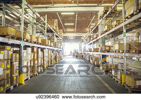 Stock Image - Forklift trucks and drivers working in distribution warehouse aisle. Fotosearch