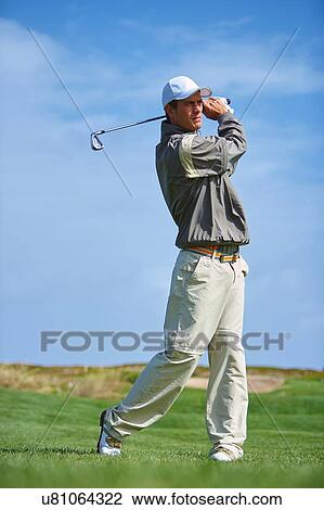 Full length front view of golfer holding golf club taking golf swing View Large Photo Image Stock Image - Full length front view of golfer holding golf club taking golf swing. Fotosearch