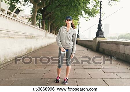 Stock Photograph - Full length portrait of female runner holding water bottle. Fotosearch