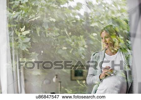 Stock Photo - Full term pregnancy young woman at home behind window. Fotosearch