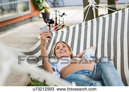 Full term pregnancy young woman lying in hammock taking smartphone selfie View Large Photo Image Stock Image - Full term pregnancy young woman lying in hammock taking smartphone selfie. Fotosearch