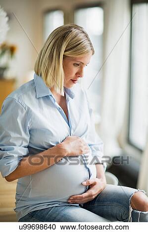Full term pregnancy young woman sitting on table View Large Photo Image Stock Image - Full term pregnancy young woman sitting on table. Fotosearch