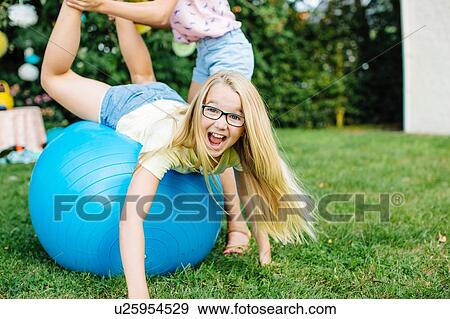 Girl balancing on fitness ball in garden View Large Photo Image Stock Photo - Girl balancing on fitness ball in garden. Fotosearch