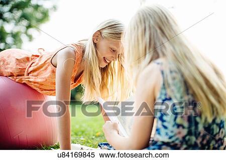Stock Photography - Girl balancing on fitness ball in garden. Fotosearch
