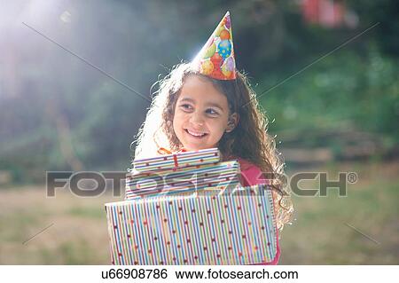 Girl carrying stack of gifts at garden birthday party View Large Photo Image Stock Photograph - Girl carrying stack of gifts at garden birthday party. Fotosearch