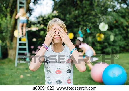 Stock Photo - Girl covering eyes at summer party. Fotosearch