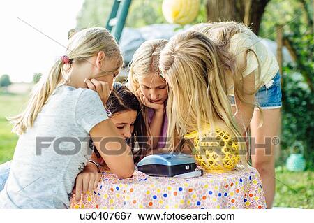 Stock Photo - Girl crowding around instant film camera at summer garden party. Fotosearch