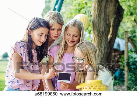 Stock Image - Girl crowding around instant photograph at summer garden party. Fotosearch