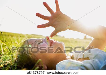 Girl lying in park shielding eyes from sunlight View Large Photo Image Stock Photo - Girl lying in park shielding eyes from sunlight. Fotosearch