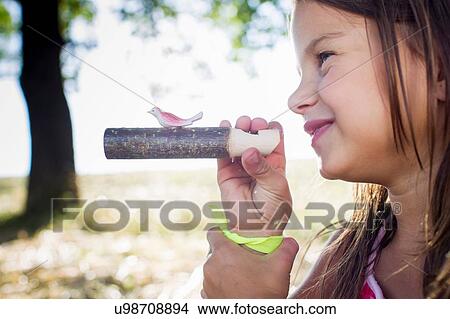 Picture - Girl preparing to blow bird whistle in park. Fotosearch