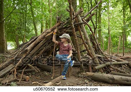 Stock Image - Girl sitting by log camp in forest, Amsterdam, Holland. Fotosearch