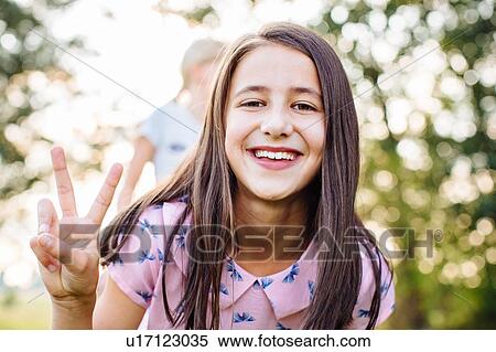 Girl smiling with peace sign in garden View Large Photo Image Stock Photography - Girl smiling with peace sign in garden. Fotosearch