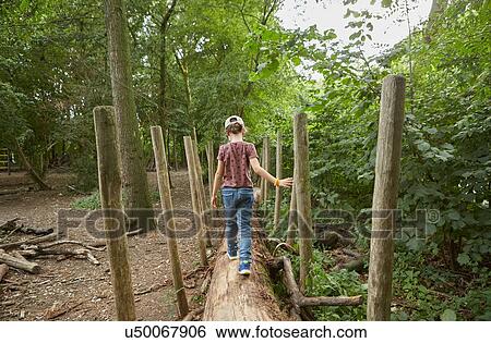 Stock Photograph - Girl walking on tree trunk in forest, Amsterdam, Holland. Fotosearch