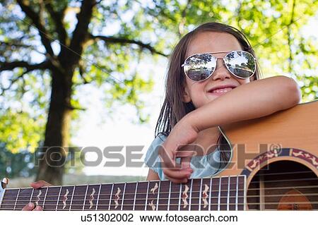 Girl wearing sunglasses posing with acoustic guitar in park View Large Photo Image Stock Image - Girl wearing sunglasses posing with acoustic guitar in park. Fotosearch
