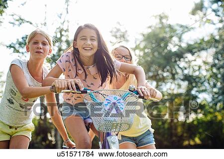Picture - Girls cycling in garden. Fotosearch