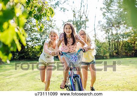 Girls cycling in garden View Large Photo Image Stock Photo - Girls cycling in garden. Fotosearch